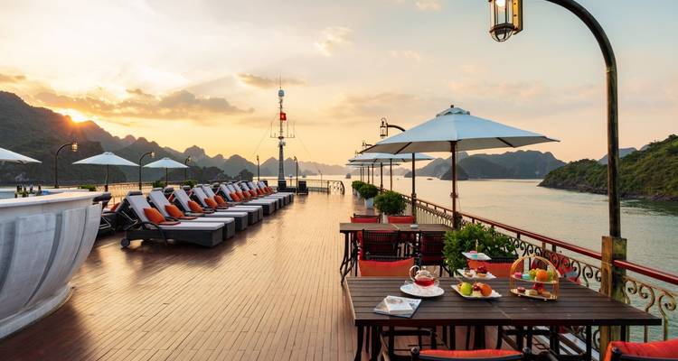 Terras met uitzicht op het water met tafels, poolbedden en schilderachtige uitzichten.