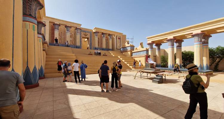 Des personnes explorant un site antique reconstitué avec une architecture de style égyptien.