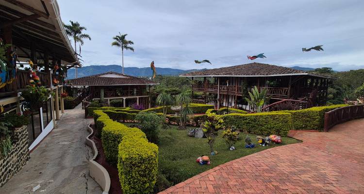 Well-kept hacienda style buildings with tiled roofs, manicured hedges and mountain backdrop in rural Colombia