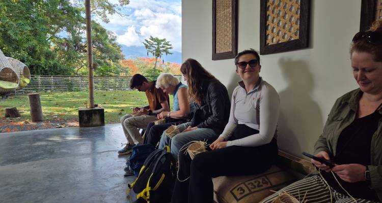 Travellers sitting on burlap coffee sacks during an indoor workshop, scrolling phones while waiting