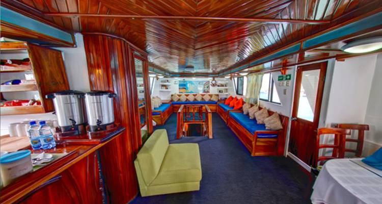 Houten lounge op het jacht met banken, kleurrijke kussens en drankstation.