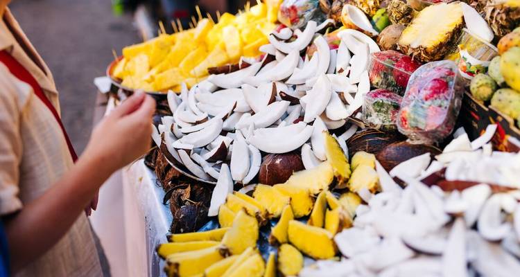 Kleurrijke marktstand volgeladen met verse ananas, kokosnoot en cactusvruchten in plakken gesneden om te proeven.