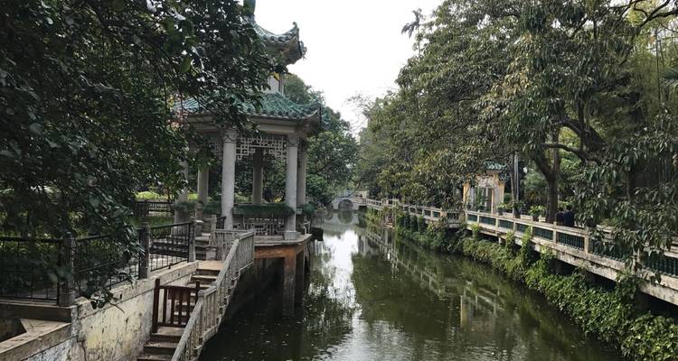 A serene waterway with a pavilion and trees.