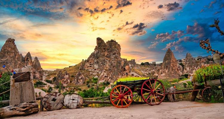 Puesta de sol sobre formaciones rocosas y estructuras antiguas en Capadocia.