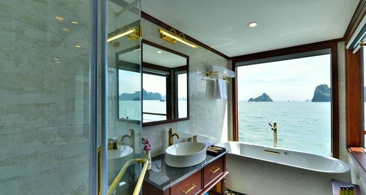 Badkamer met een bad en raamzicht op het water.