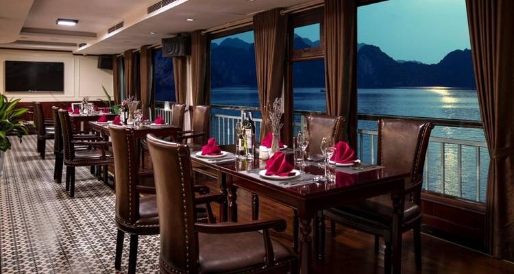 Eetgedeelte binnen een boot met uitzicht op een baai bij schemering.