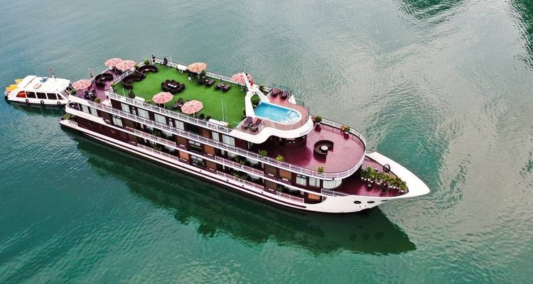 Een prachtige jacht met een groen dek en zwembad varend op helder water.