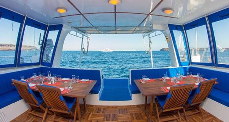 Área de comedor al aire libre en un catamarán con mesas bien organizadas con vista al mar.
