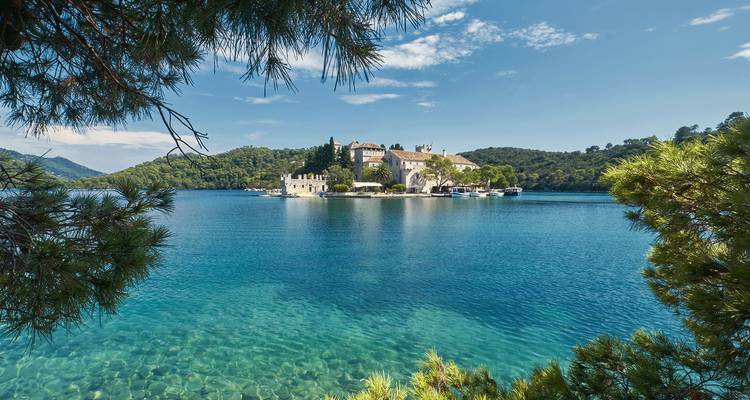 Vue panoramique d'un monastère insulaire au-dessus d'eaux claires.