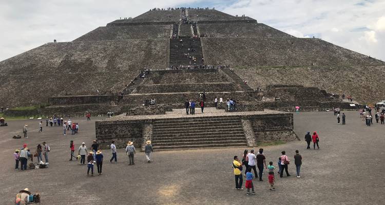 A pyramid structure at an archaeological site with visitors.