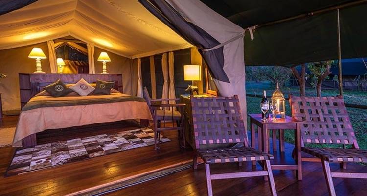 Luxuriöse Zeltunterkunft mit Lampen und Stühlen unter einem Baldachin.