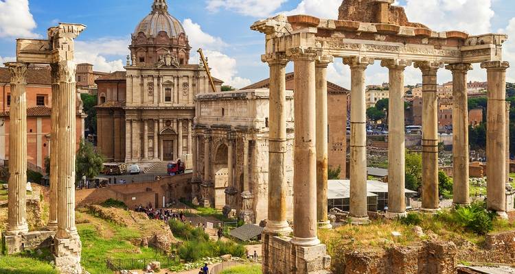 Ruines romaines antiques avec une église en arrière-plan par une journée ensoleillée.