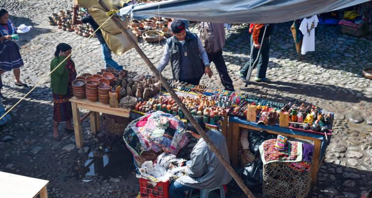 Scène de marché avec des vendeurs et de l'artisanat coloré.