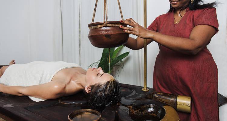 Une personne recevant un soin traditionnel à l'huile dans un cadre de spa.