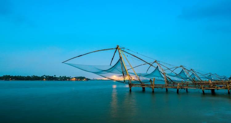 Filets de pêche chinois traditionnels au bord d'une mer calme au crépuscule.