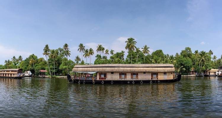 Péniche traditionnelle sur un bras mort tranquille entourée d'arbres.