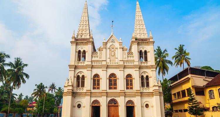 Église historique avec de hautes flèches et un environnement tropical.