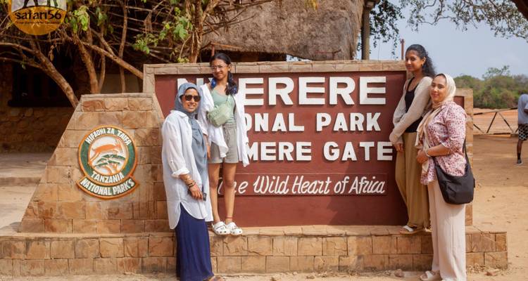 Friends posing beside the entrance sign of Nyerere National Park at Mtemere Gate, Tanzania.