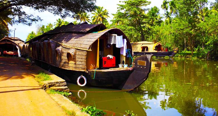 Hausboote entlang der üppigen Backwaters mit tropischer Vegetation.
