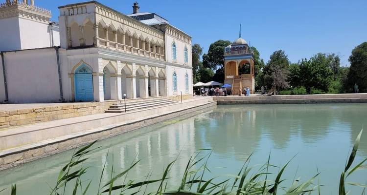 Historic building by a serene water body with people in the area.