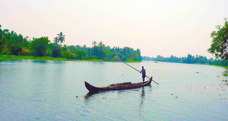 Personne ramant dans un canoë traditionnel sur une rivière.