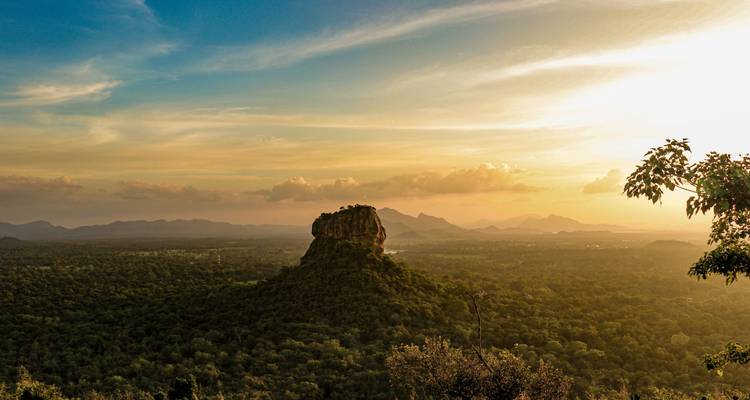 Vue panoramique du rocher de Sigiriya entouré de forêt sous un ciel lumineux.