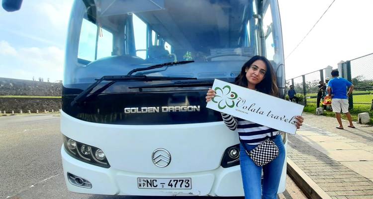Femme debout près d'un autobus de voyage tenant une pancarte.
