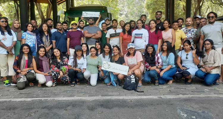 Grand groupe de personnes posant devant un bus en tenant une pancarte.