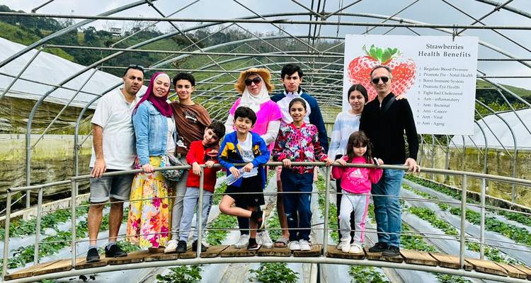 Family posing for a photo in a strawberry farm under a greenhouse.