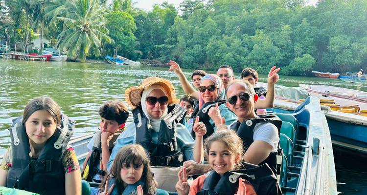 Family group enjoying a boat trip on a river surrounded by greenery.