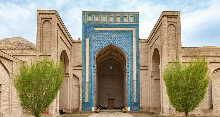 A mosque with a grand decorated entrance and matching blue tile work.