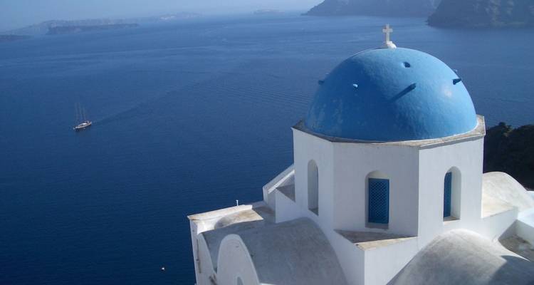 Ikonische blaudomige weiße Kirche mit Blick auf das tiefblaue Ägäische Meer in Santorin