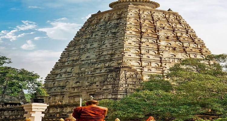 Mahabodhi-Tempelkomplex mit großer Pagode und einem Mönch im Vordergrund.