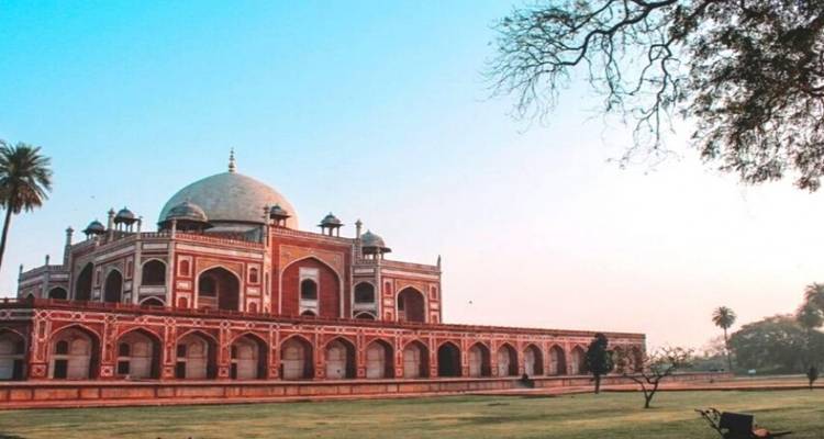 Large mausoleum with an expansive lawn under a clear sky.