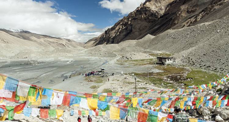 Gebedsvlaggen in een bergachtige vallei met een paar mensen.