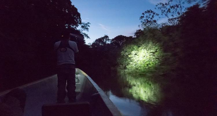 Nächtliche Bootsfahrt durch einen Fluss mit einer Taschenlampe.