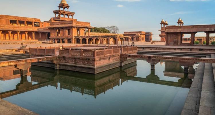 Oud architecturaal complex met een spiegelende vijver.