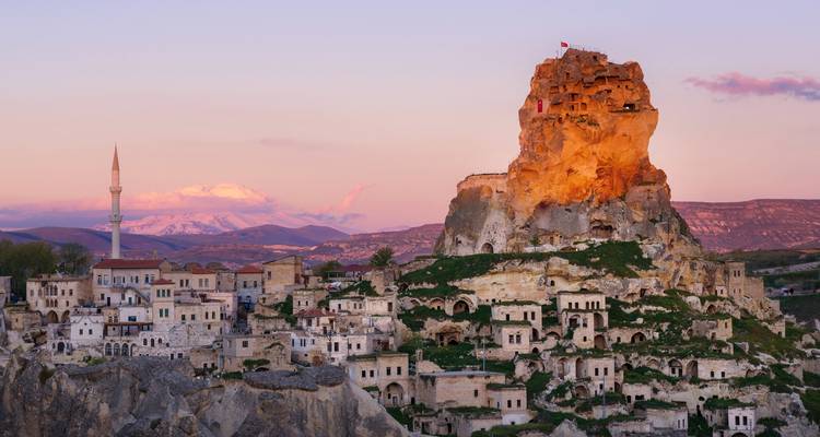 Dramatische rotsformaties en oude woningen bij zonsondergang.