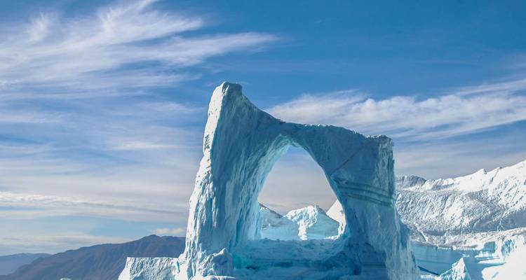 Grote ijsformatie met een boog onder een blauwe hemel.