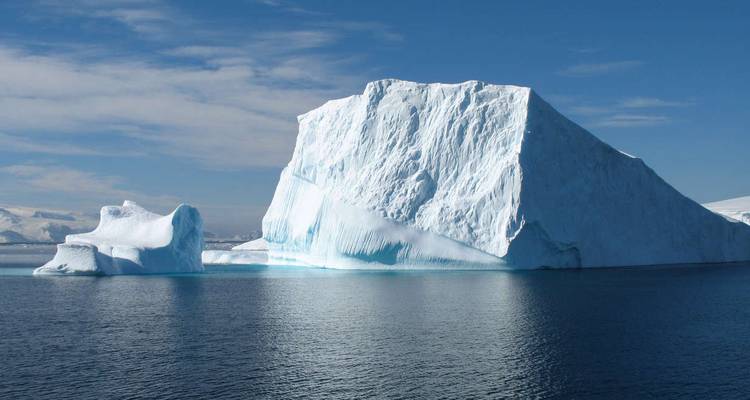 Grote ijsberg drijvend in kalme wateren onder een heldere hemel.