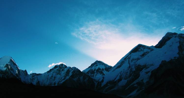 Bergtoppen die zich aftekenen tegen een schemerlicht.