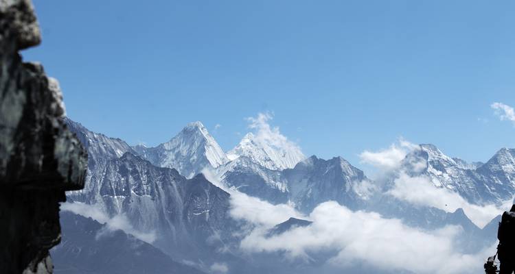 Himalayatoppen met wolken in een heldere blauwe lucht.