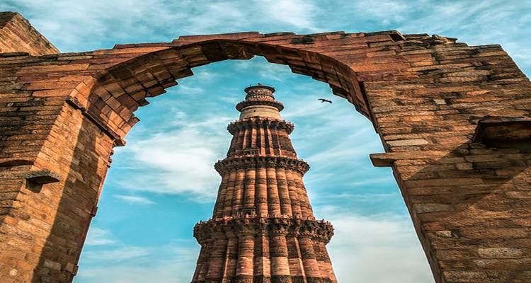 Hoher, alter Turm, umgeben von einem Bogen unter einem blauen Himmel.