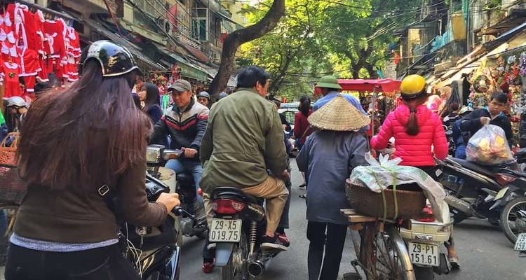 Bustling market street crowded with people and motorbikes.