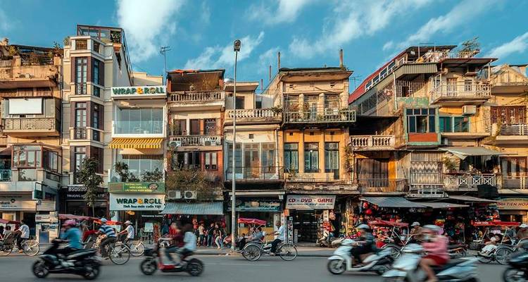 Bustling street scene with motorbikes and traditional buildings in an urban area.