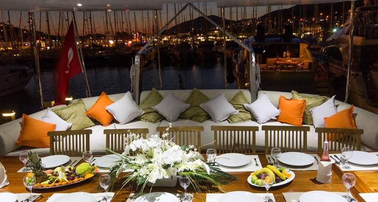 Luxurious dining setup on a yacht with night lights of a marina.
