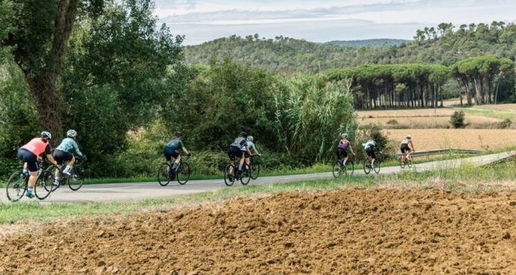 Cyclistes tournant au coin d'une route rurale avec un paysage pittoresque en arrière-plan.