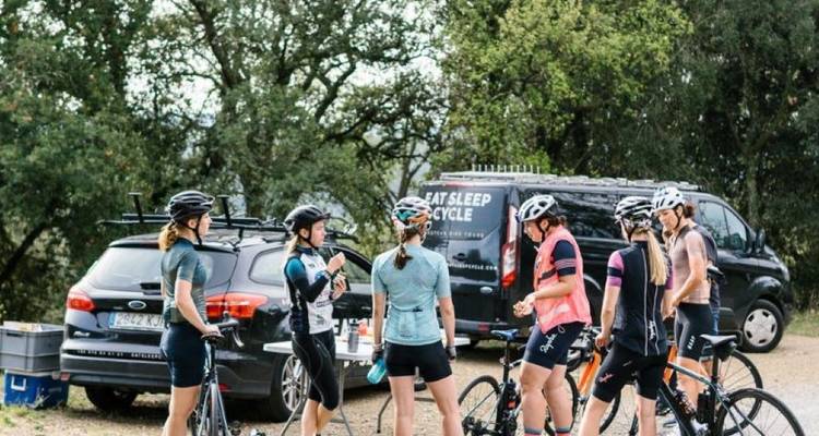 Groupe de cyclistes se reposant dans une zone boisée avec des véhicules d'assistance.