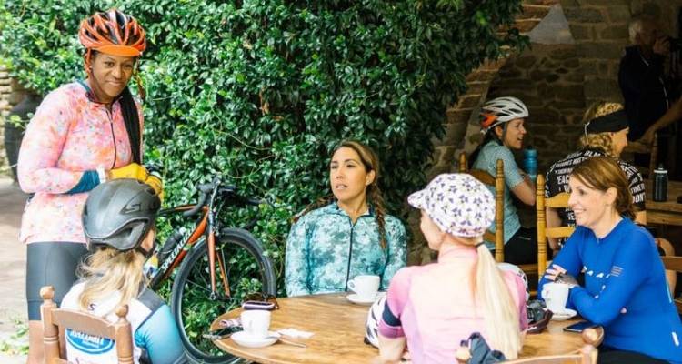 Des cyclistes se reposent dans un café en prenant une boisson.