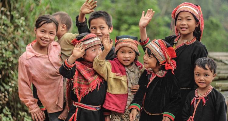 Groupe d'enfants locaux souriants qui saluent de la main devant la caméra.